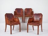 quatre fauteuils en cuir marron placés les uns à côté des autres sur une surface blanche