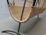 une chaise en osier avec une structure métallique posée sur une surface blanche