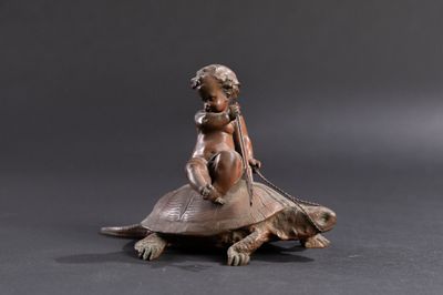 bronze figurine of a child on a turtle on a black background