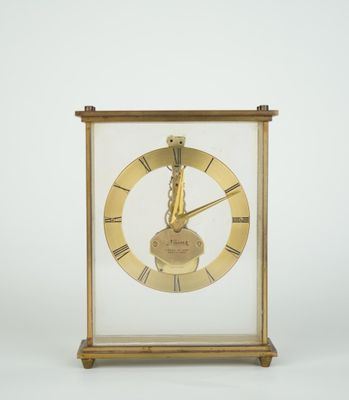 une image représentant une horloge dorée dans une vitrine, sur fond blanc