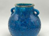 un vase bleu muni d'anses sur fond blanc