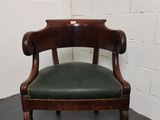 an antique wooden chair with green leather upholstered seat