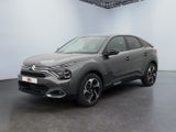 Une voiture grise est garée dans une grande pièce au sol noir.