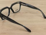 glasses on a wooden table with a black frame and clear lens