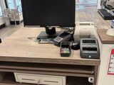 a desk with a computer and a printer on it in a store