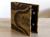 an image of a snake skin wallet sitting on top of a wooden table
