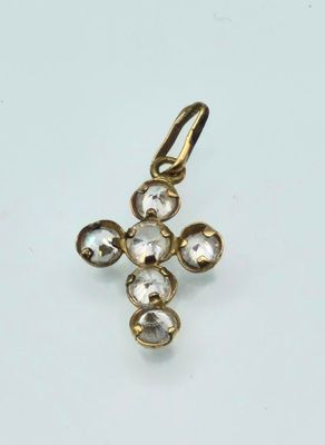 a close up of a gold cross pendant on a white surface