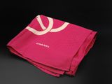 pink towel with white logo on it on a black surface