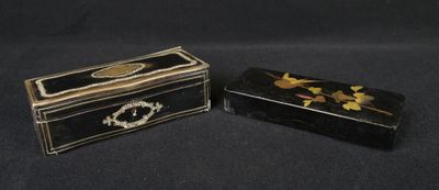 deux boîtes noires et dorées ornées de fleurs, posées sur un fond noir