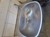 a sink in the corner of a bathroom with a hose on the wall