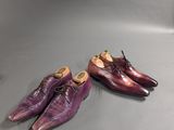 two pairs of purple shoes sitting on top of a table