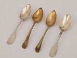 four silver spoons are lined up in a row on a white surface