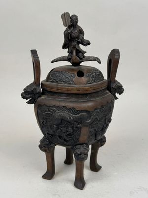 an antique bronze incense box with a statue on top of it