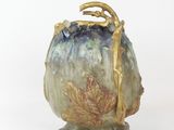 a small vase with a gold handle on a white surface