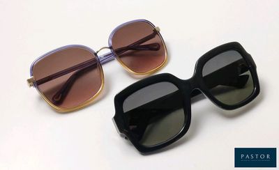 two pairs of sunglasses sitting on top of each other on a white surface