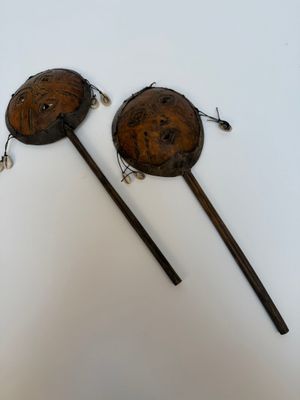 une paire de cuillères en bois ornées de visages sculptés, posées sur une surface blanche