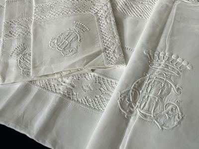 plusieurs serviettes blanches brodées, ornées de monogrammes, posées sur une table