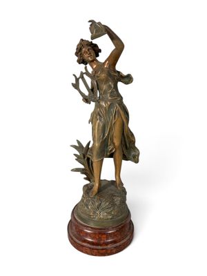 bronze statue of a woman holding a bird on a wooden base