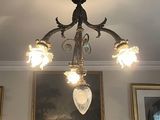un lustre dans une pièce où sont accrochés des tableaux aux murs