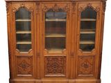 une bibliothèque en bois avec des portes vitrées et des sculptures sur la façade