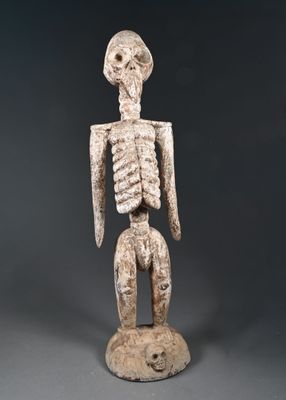 une statue représentant un squelette posé sur un socle en bois