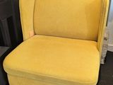une chaise jaune aux pieds noirs devant une cheminée, avec un feu de cheminée en arrière-plan