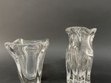 two clear glass vases on a black surface with a gray background