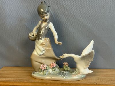 une figurine représentant une femme et un canard posée sur une table