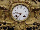 a gold clock with a white face on a black background
