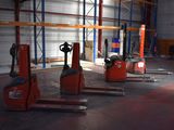 several forklifts are parked in a large warehouse with lots of pallets
