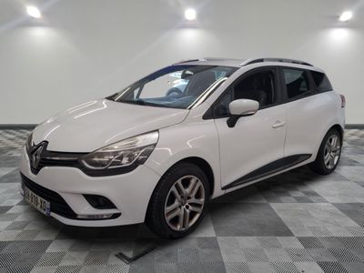 une voiture blanche est garée dans une pièce au sol à carreaux