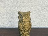 a gold owl figurine sitting on a wooden table