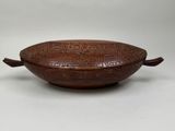 an old wooden bowl with carvings on it sitting on a white surface