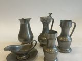 three silver vases and a saucer on a white surface