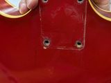 a person holding a red guitar in a store
