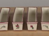 a set of four white and pink dishes on a table