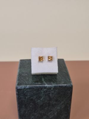 une paire de boucles d'oreilles en or posées sur un bloc de marbre, lui-même posé sur un autre bloc de marbre