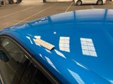 a blue car parked in a parking lot with a sticker on it