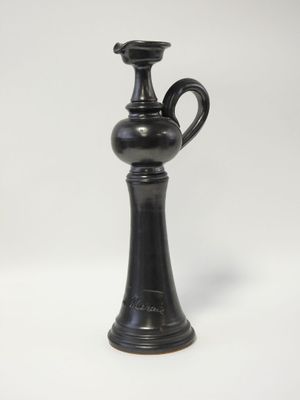 un vieux vase noir posé sur une table blanche