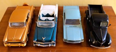 Plusieurs petites voitures sont alignées sur une table devant un mur.
