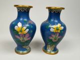 pair of blue vases with yellow flowers on them on a white surface