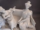 a statue of two women sitting on a couch playing a musical instrument