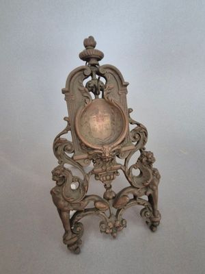 une horloge en argent posée sur une chaise en bois