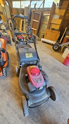 Plusieurs tondeuses à gazon sont alignées dans un garage