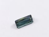 a green tourmaline stone with a rectangular shape on a white surface