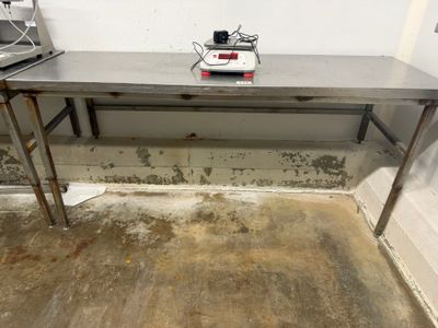 une table en métal sur laquelle se trouve une balance, dans une pièce