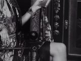 black and white photograph of a woman sitting on a chair holding a tea pot