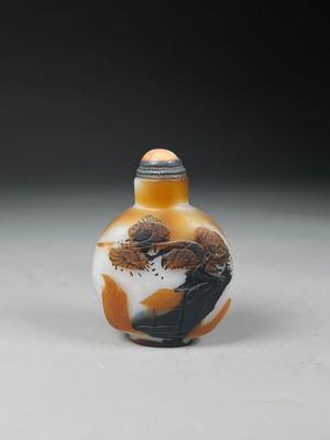 une fiole à tabac en verre orange et blanc posée sur une table