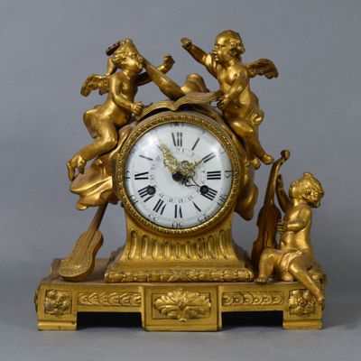 a gold clock with angels on it on a table