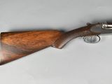 a close up of a gun with a wooden handle on a white surface